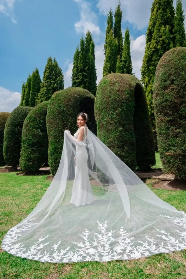 Novia con velo largo en los jardines del venue